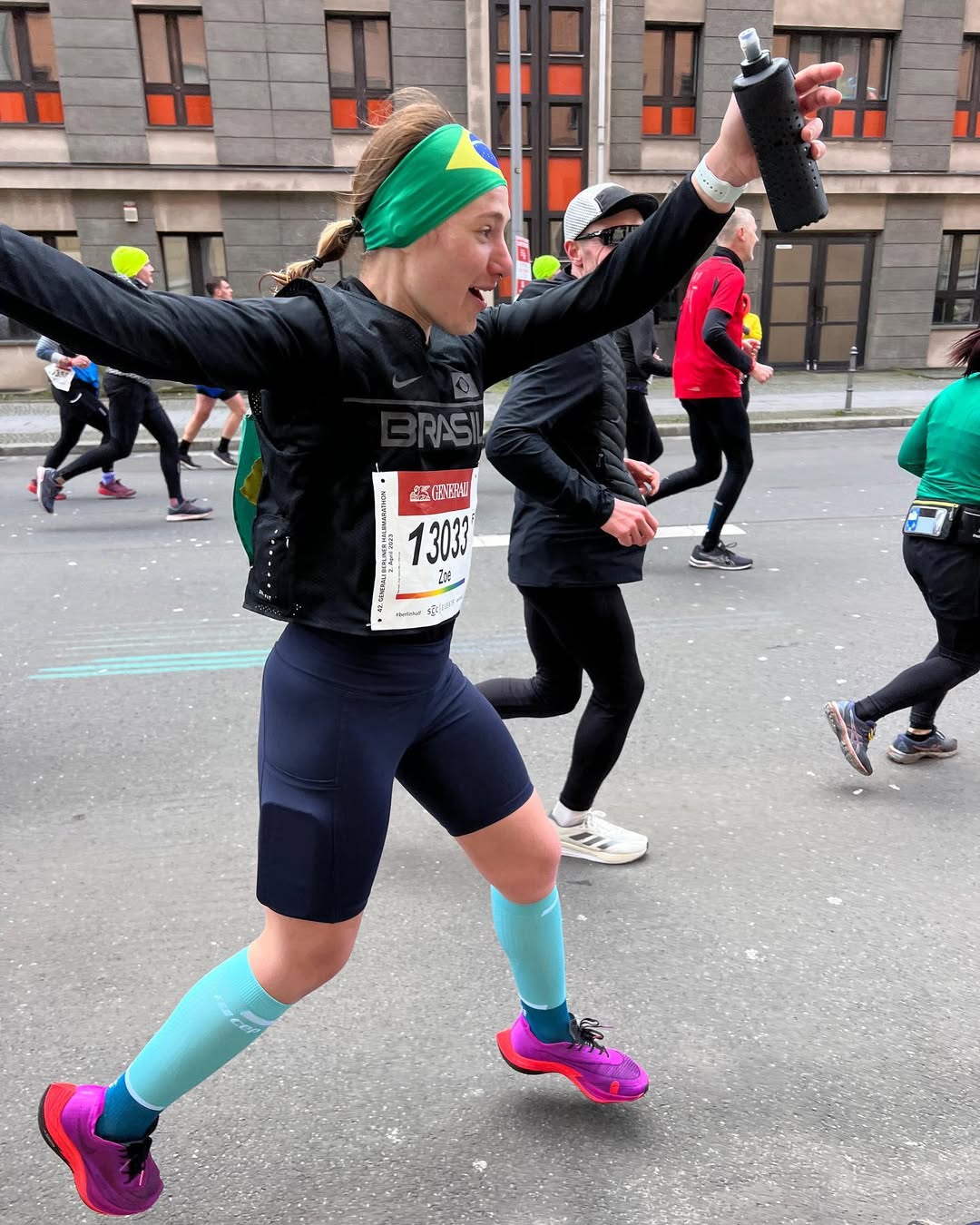 Zoe Barossi correndo a Meia Maratona de Berlim com faixa brasileira